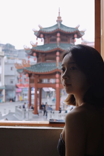 站在窗前向城市中的塔看去的一个年轻女子