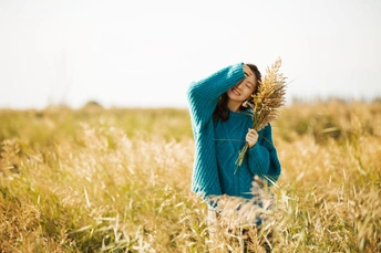 一位身穿蓝色衣服的年轻女子站在麦田里 抱着一个人