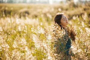 一个年轻的女人坐在高高的草地上晒太阳