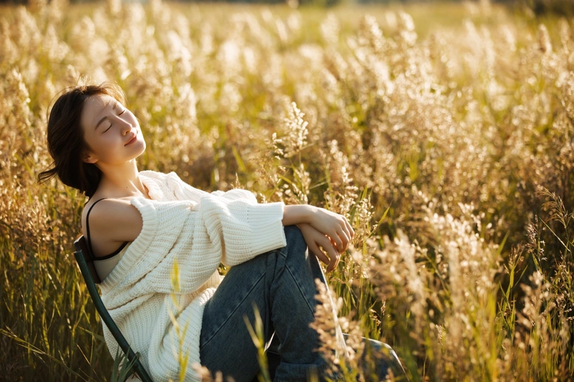 年轻漂亮的女人坐在高高的草地上的椅子上