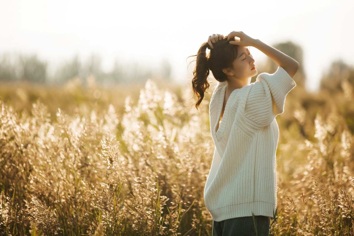 一张年轻女子双手高举站在草地上的照片