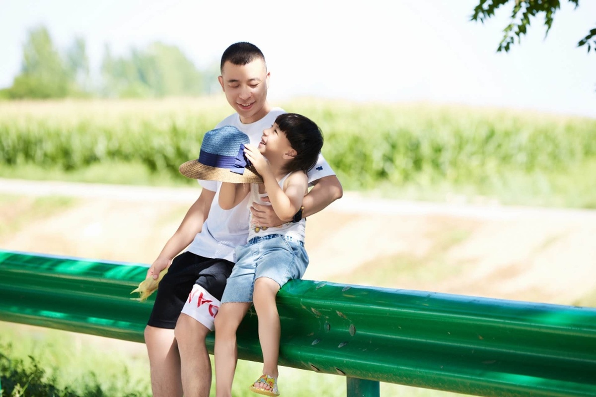 一个年轻男孩和一个小女孩站在公园里 和他们的父亲在一起。