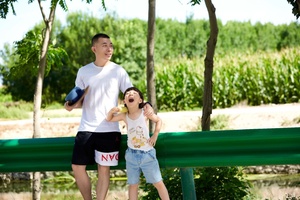 一个年轻男子和一个年轻女子站在公园里一个男孩旁边。