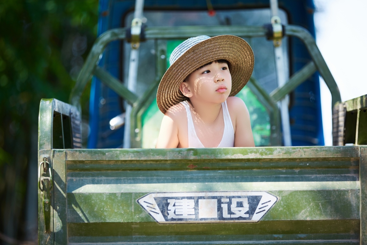 一个小女孩戴着帽子坐在卡车里 还有一个小男孩。