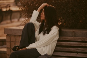 一个穿着白衬衫的女人坐在长凳上