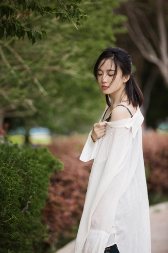 一位穿着白色衬衫和牛仔裤的年轻女子站在外面