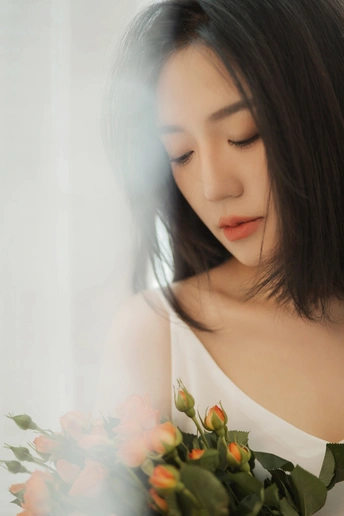 一位美丽的年轻女子嗅着一束白色玫瑰的肖像