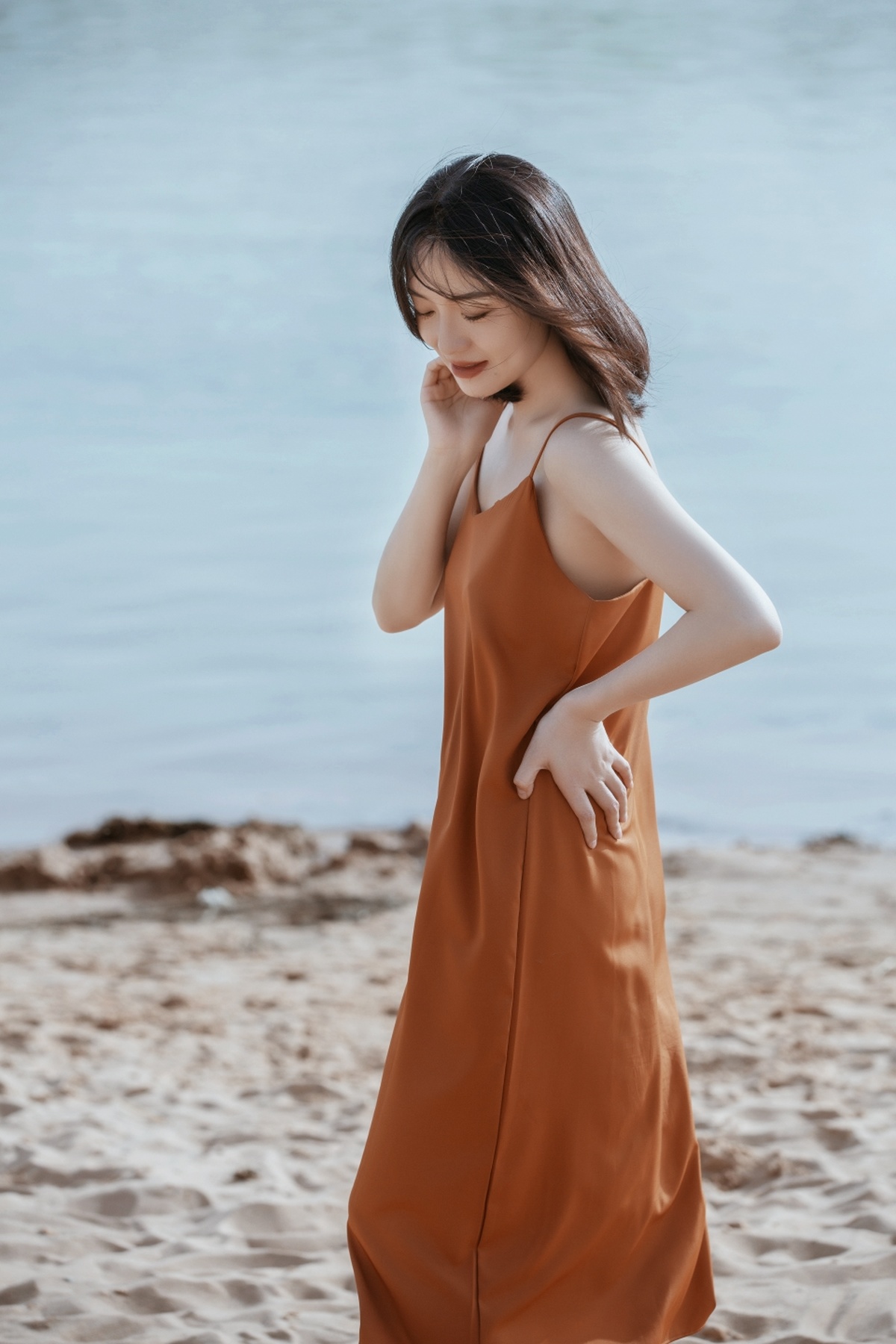 橙色连衣裙的年轻女子在沙滩上行走