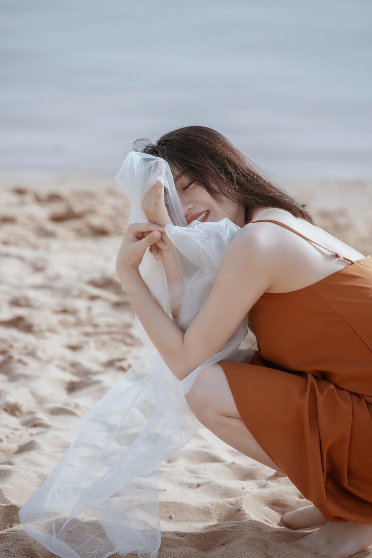 美丽的年轻女子穿着白色连衣裙在海滩上摆姿势