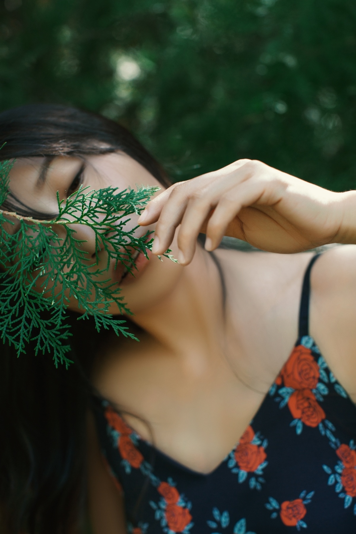 一位年轻女子举着绿色植物的树枝在面前 并遮住她的眼睛
