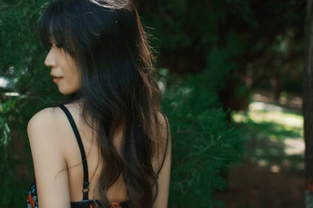 一位长发着黑色连衣裙的年轻女子站在森林中
