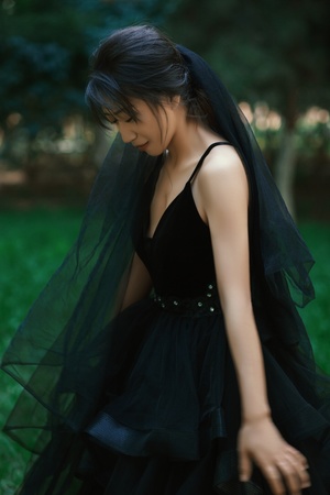 一个穿着黑色连衣裙和面纱的女孩在森林中