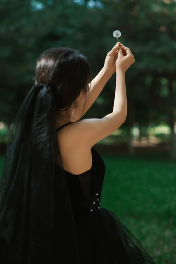 一位穿着黑色连衣裙的年轻女子抱着花
