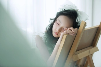 一个小女孩坐在靠近画架的椅子上 正在看窗外 免费照片