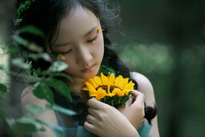一位美丽的年轻女子举着黄色的花靠近她的脸