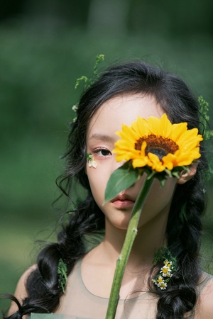 一位年轻女子抱着向日葵对着脸