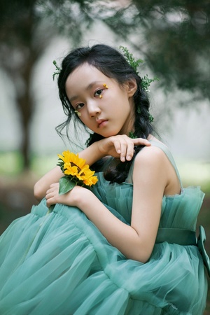 一位穿着绿色连衣裙 带着美丽向日葵的年轻女孩