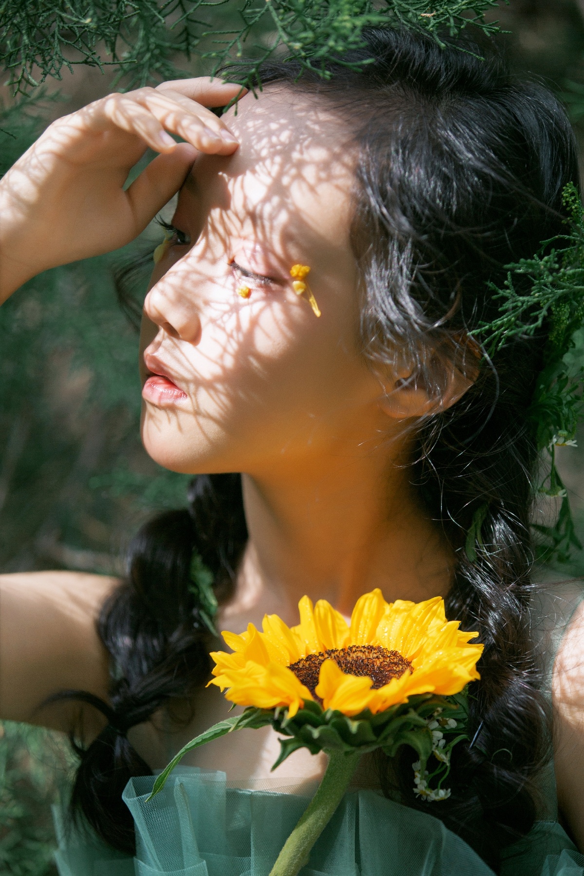 一位年轻女子举着黄色的花挡在脸前 身处绿色的森林中。