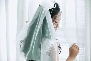 一个年轻女孩在窗前 窗帘是白色的 头戴面纱。
