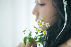 一位年轻女子将一朵小雏菊放在她的脸上