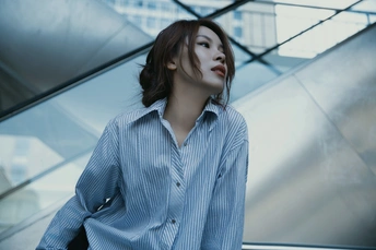 站在自动扶梯前的蓝色衬衫年轻女子
