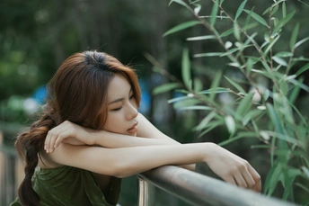 美丽的年轻女子在夏日绿色的花园中倚靠在围墙上 这张照片是精选的