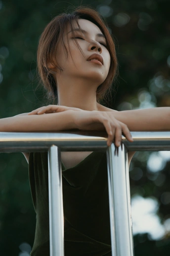 一位穿着黑色衣服的年轻女子闭着双臂 靠在栏杆上 准备拍摄肖像。