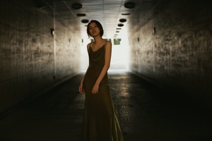一个穿着绿色连衣裙的女人沿着一条长长的走廊走下去 走廊尽头有一盏灯。