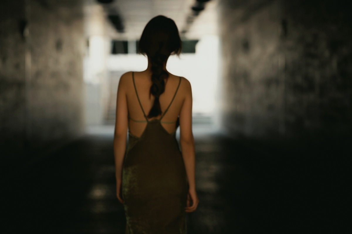 一个穿着黑色连衣裙的女孩走在一条走廊里