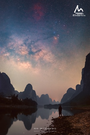 一个人站在湖边 晚上看着天上的星星和山。
