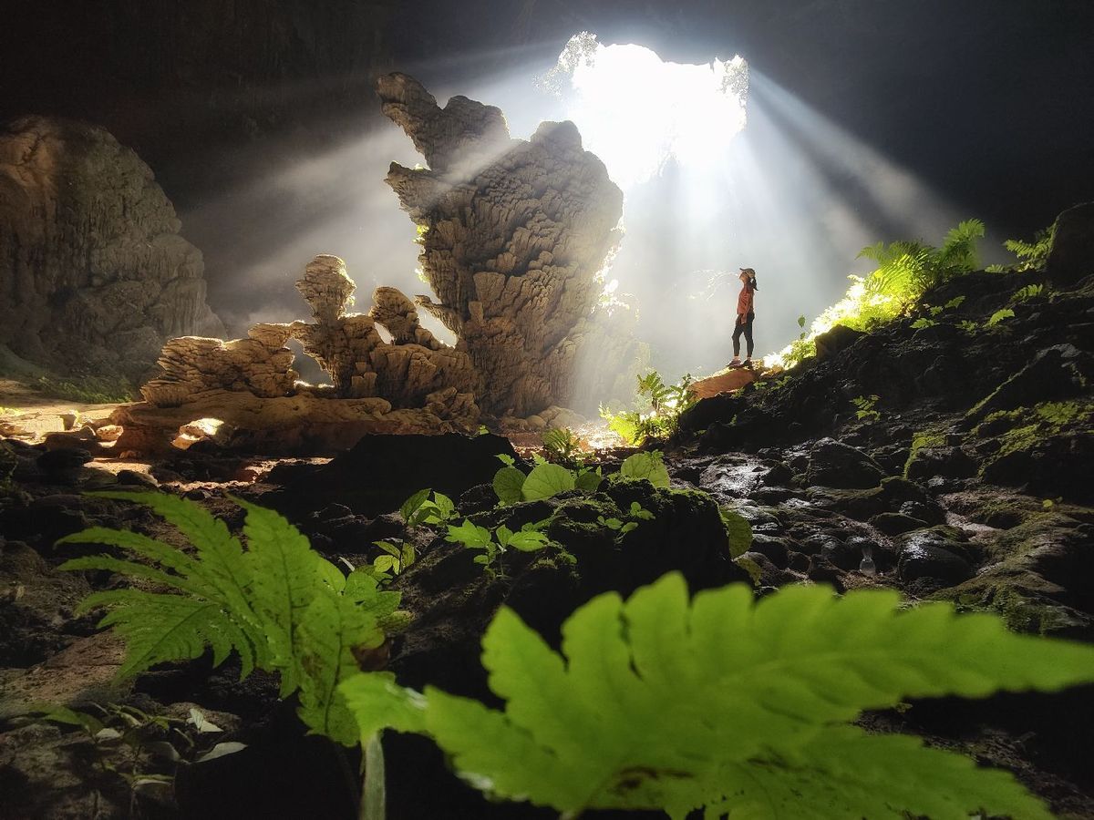 一个夜晚站在洞穴岩石上的男子 身上有光照亮他。