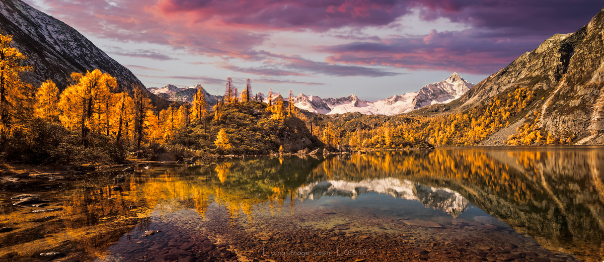 一个有树木和山脉的湖泊 天空色彩斑斓