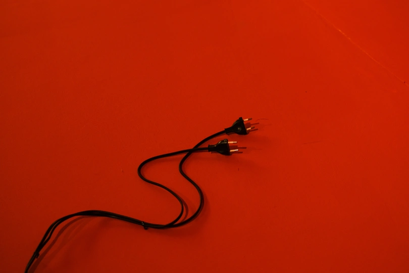 在一张桌子前面的一堵红墙上的一个黑色绳子。