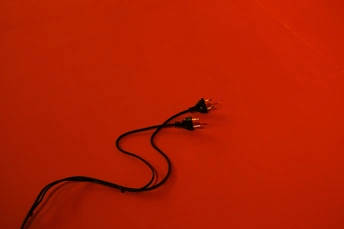 在一张桌子前面的一堵红墙上的一个黑色绳子。