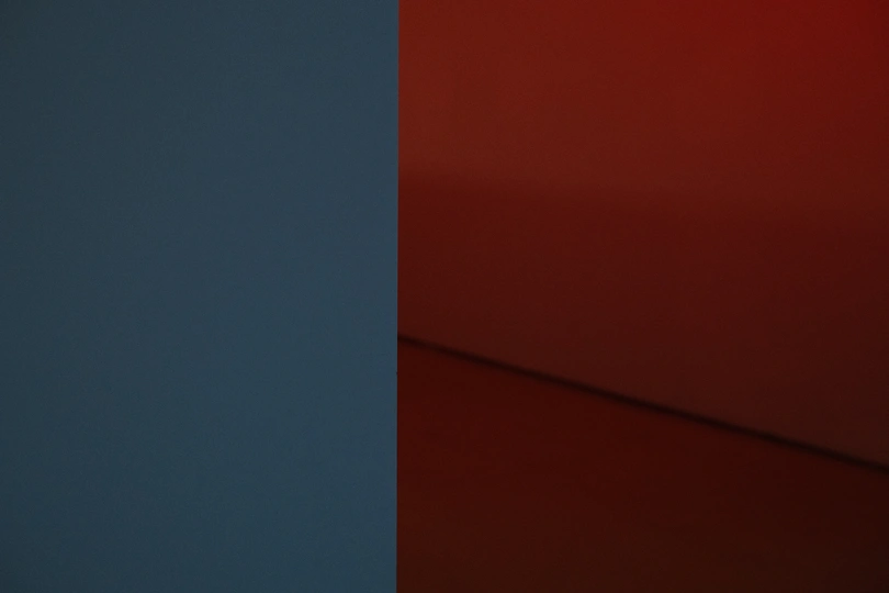 一只蓝色的花瓶坐在红色的墙上 在一个房间里。