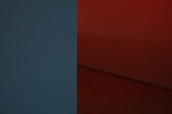 一只蓝色的花瓶坐在红色的墙上 在一个房间里。