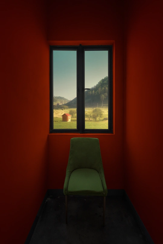 一把绿色的椅子坐在一个空荡荡的房间里 墙壁是红色的。