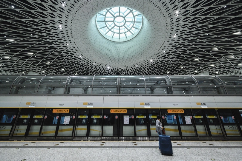 一张照片 一个人站在火车站 带着行李和手提箱。