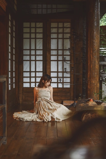 一个穿着白色连衣裙的年轻女子坐在美丽房间的地板上