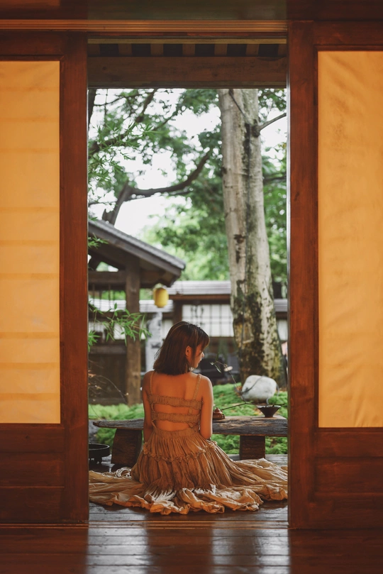 一位穿着连衣裙的年轻女子坐在门前地板上