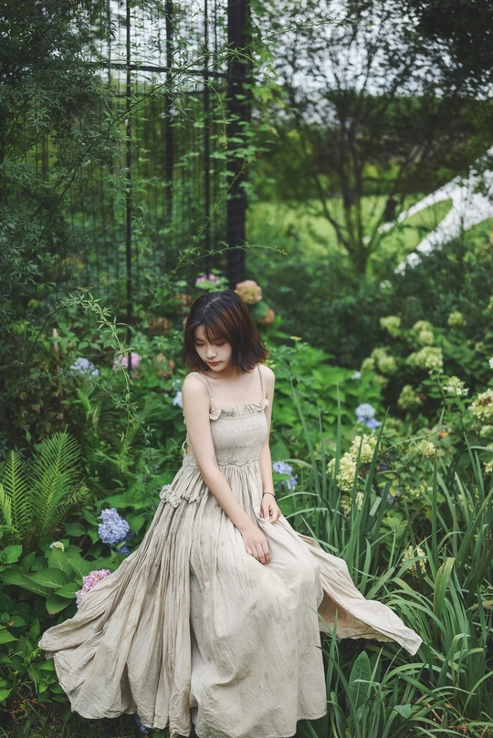 一位穿着白色连衣裙的年轻女子在花园里