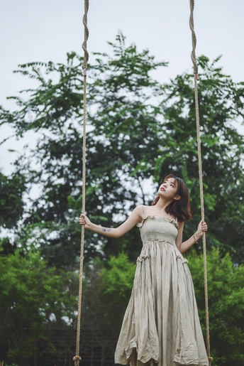 一位年轻女子在树上挂着的一架秋千上荡漾。