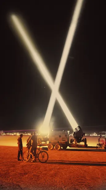 一个站在车辆旁边 在天空中的光束下的自行车男子