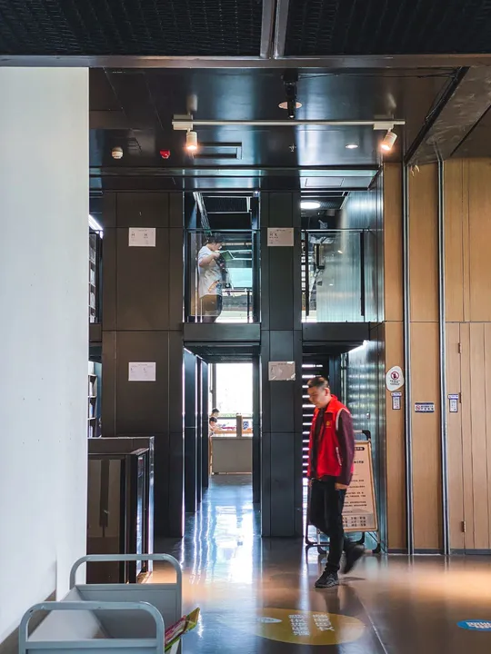 一个人穿着红衣服正在走下二楼的走廊