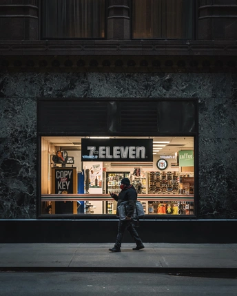 一个男人在晚上走在街前商店