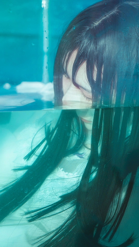 一个女人在蓝色的池水里游泳