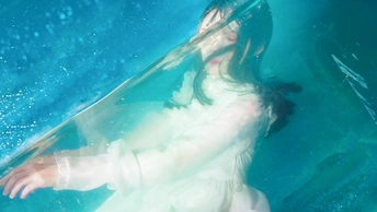 一个穿着白色连衣裙的女人在蓝色的水箱里游泳