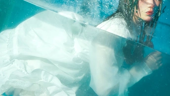 一个穿着白色连衣裙的女人在蓝色的水下