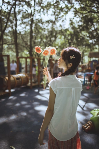 站在游乐场前的花束年轻女子