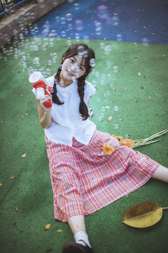 一个小女孩抱着花坐在草地上